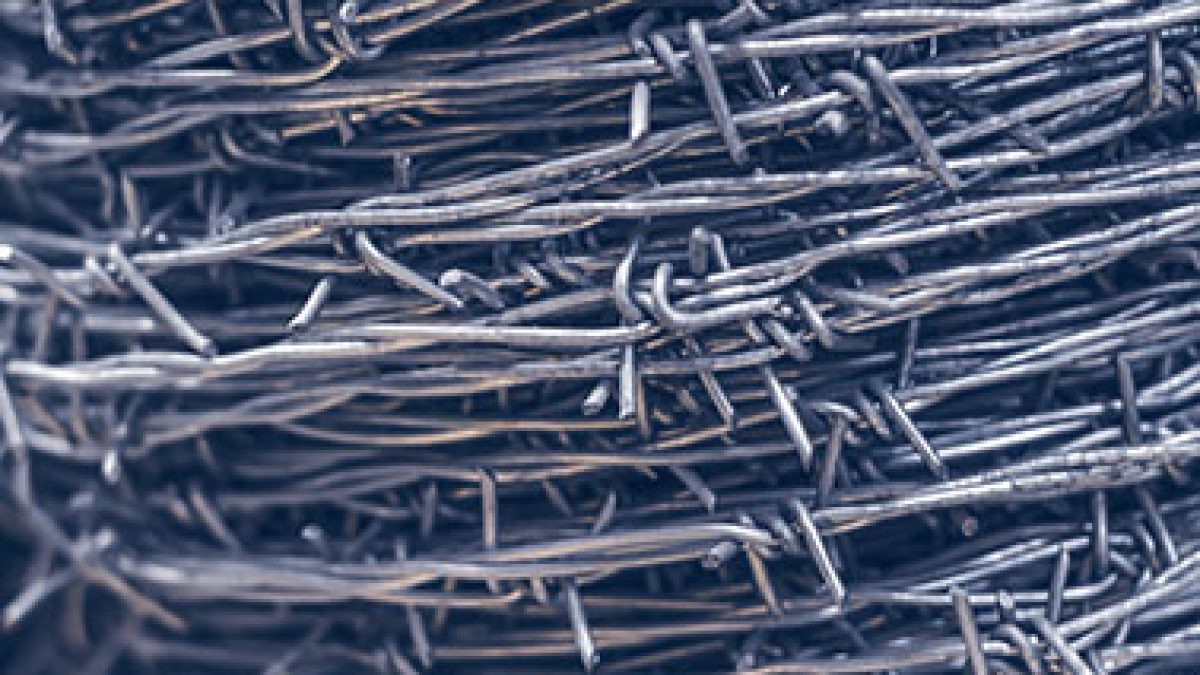 Close Up On A Pile Roll Of Shiny New Barbed Wire For Fence
